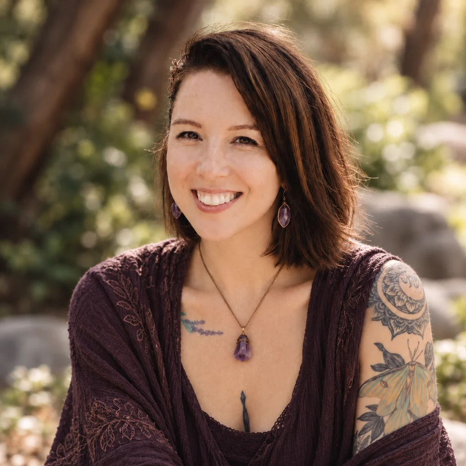 Deb smiling outdoors in amethyst jewelry and a deep plum outfit